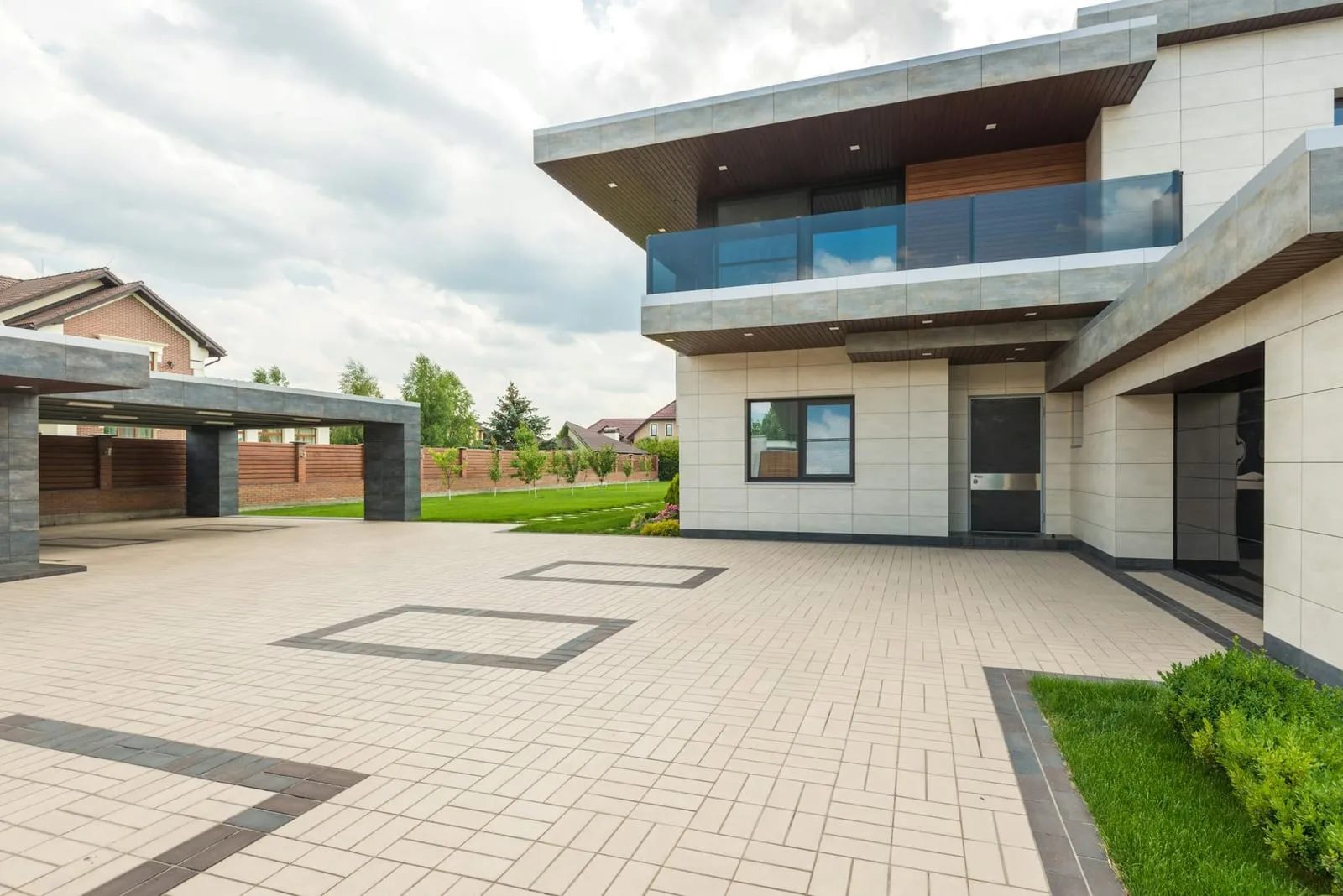 Two-storey modern house with a glass balcony and a paved driveway