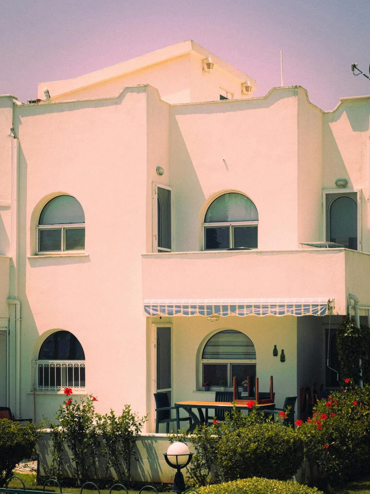 Pink Mediterranean-style house with arched windows and a shaded terrace
