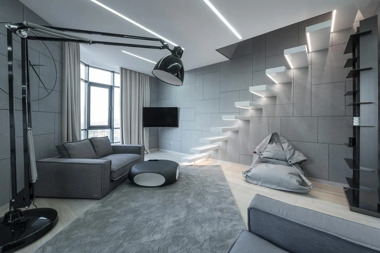 Grey living room with a floating staircase and linear ceiling lights